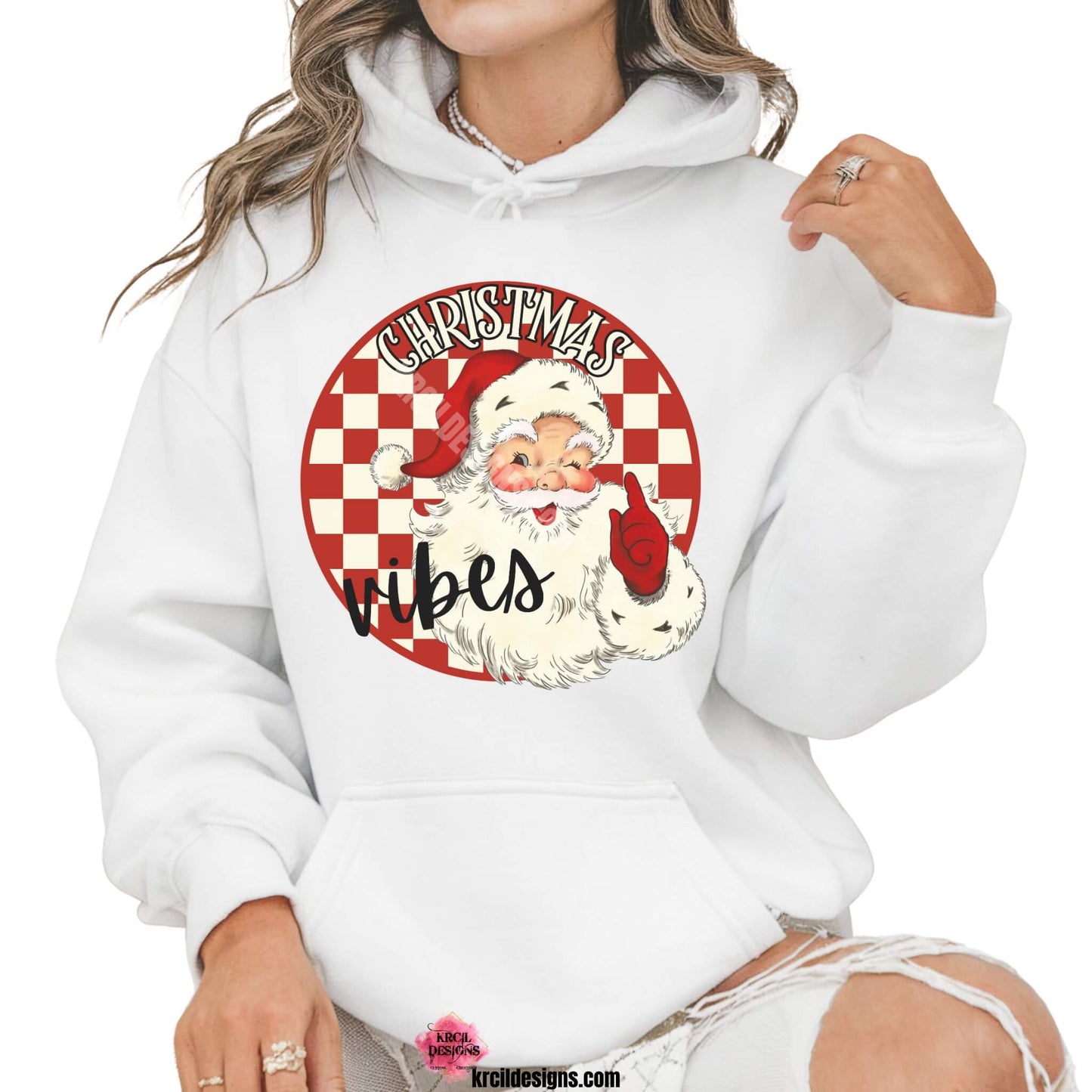 Christmas Sweaters by KrcilDesigns.com | Graphic design on a white hoodie, features a vintage-style Santa Claus with rosy cheeks, winking and pointing, set against a red and white checkered circle background with text that reads: "Christmas Vibes" in bold cream vintage Christmas letters outlined in black.