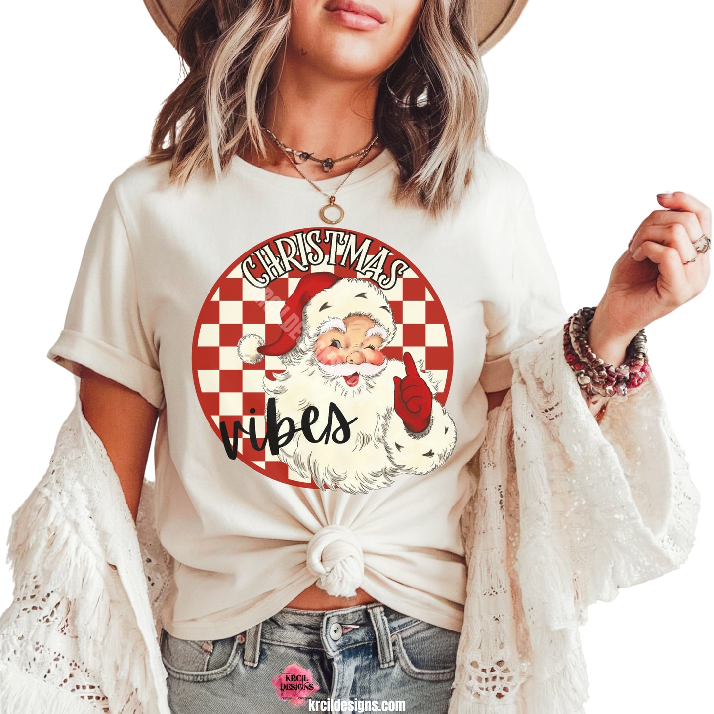 Christmas Tees by KrcilDesigns.com | Graphic design on a white t-shirt, features a vintage-style Santa Claus with rosy cheeks, winking and pointing, set against a red and white checkered circle background with text that reads: "Christmas Vibes" in bold cream vintage Christmas letters outlined in black.