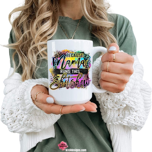 Sassy Mom Funny Coffee Mugs by KrcilDesigns.com | Graphic design on a white ceramic mug featuring bold, colorful text that reads "Because Mama Runs This Shitshow" The word "Mama" is in a vibrant rainbow script with leopard print accents, and the background includes a splash of bright paint textures in yellow, teal, pink, and purple. The style is playful, edgy, and sassy—perfect for fun-loving moms with a sense of humor.