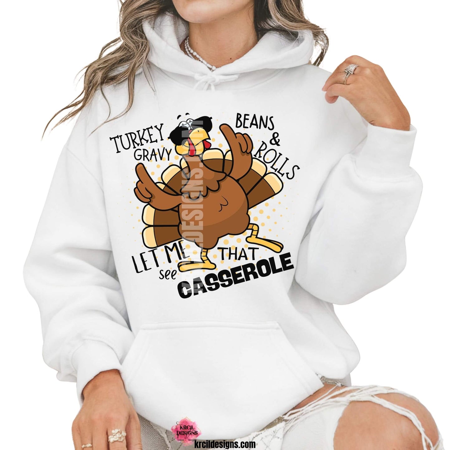 Funny Thanksgiving Shirts by KrcilDesigns.com | Graphic design on a white hoodie, featuring a cartoon turkey wearing sunglasses, the turkey is brown with a red wattle, yellow beak and feet, with yellow dots as a background. The words are scattered around the turkey in bold black text that reads: "Turkey Gravy Beans & Rolls LET ME SEE THAT CASSEROLE"