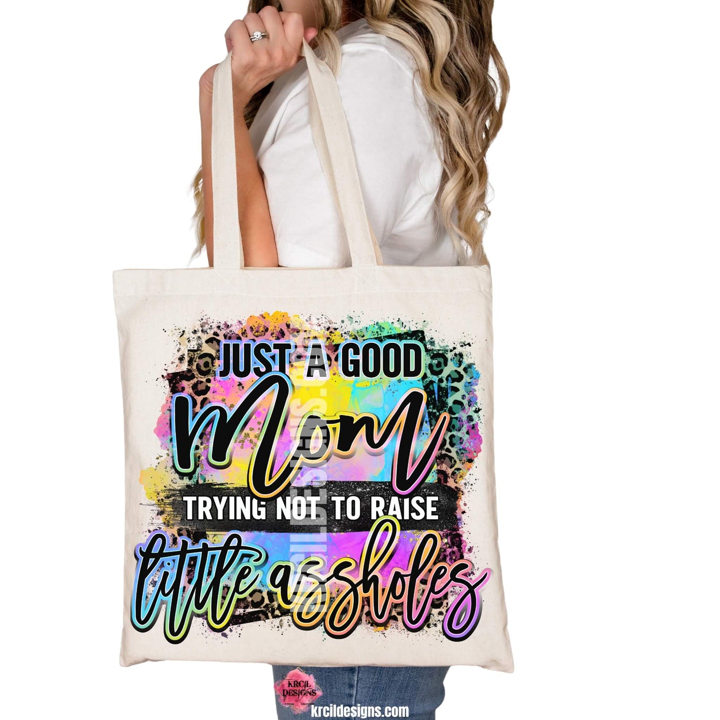 Sassy Mom Tote Bags by KrcilDesigns.com | Graphic design on a canvas tote bag featuring bold, colorful text that reads "Just A Good Mom Trying Not To Raise Little Assholes" The word "Mom" is in a vibrant rainbow script with leopard print accents, and the background includes a splash of bright paint textures in yellow, teal, pink, and purple. The style is playful, edgy, and sassy—perfect for fun-loving moms with a sense of humor.