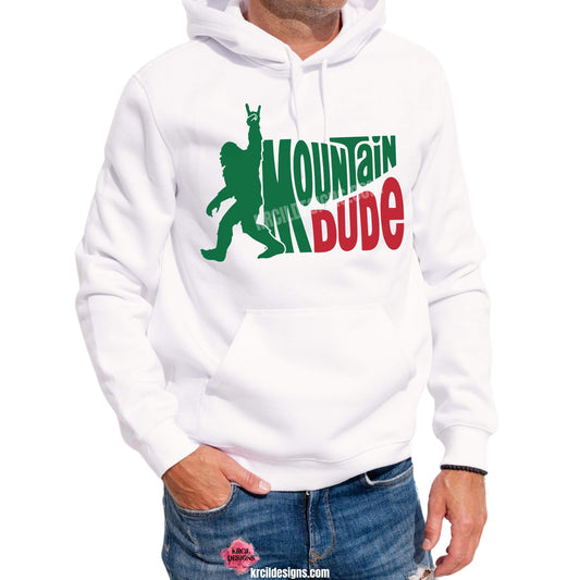 Bigfoot Shirts by KrcilDesigns.com | Graphic design on a white hoodie, featuring a green silhouette of Bigfoot walking with one arm raised and using a rock-on hand gesture, next to the figure, in waved bold capital letters text that reads: "MOUNTAIN DUDE," with "MOUNTAIN" in green and "DUDE" in red.