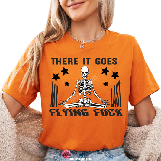 Sassy Graphic Tees T-Shirts by KrcilDesigns.com | Graphic design on a orange t-shirt, featuring bold black text that reads: "There It Goes My Last Flying Fuck" with a meditating skeleton.