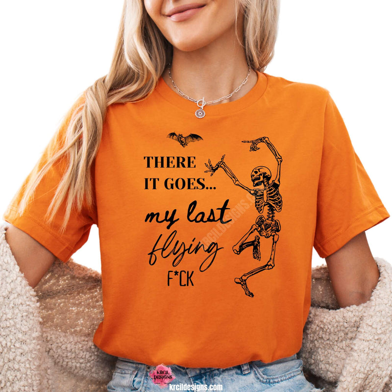 Sassy Graphic Tees T-Shirts by KrcilDesigns.com | Graphic design on a orange t-shirt, featuring bold black text that reads: "There It Goes My Last Flying F*ck" with a bat and a dancing skeleton.