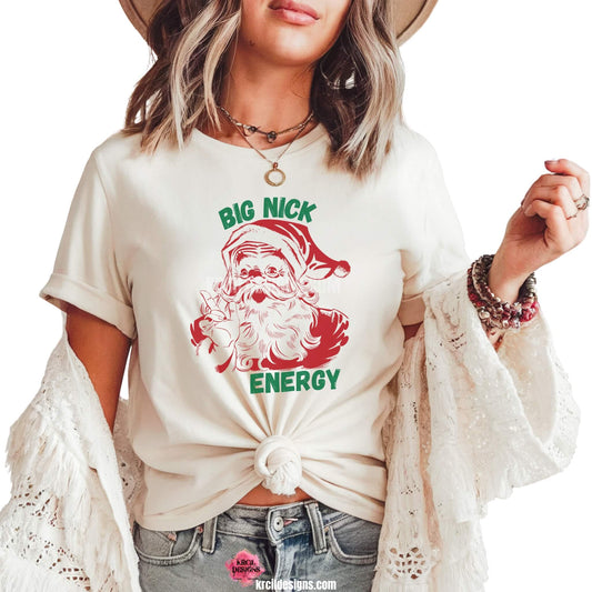 Christmas Tees by KrcilDesigns.com | Graphic design on a white t-shirt, features a vintage-style red Santa Claus, waving and pointing his index finger, with text that reads: "Big Nick Energy" in bold capital green block letters.