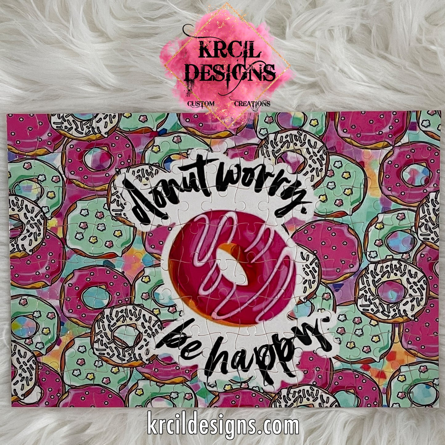 "Donut Worry Be Happy" Puzzle by Krcil Designs | Get ready for a slice of heaven! This playful donut-themed puzzle is sweeter than a dozen donuts and is as educational as it is fun. It's a delightful challenge that makes a perfect gift for puzzle enthusiasts of all ages. Fully assembled and complete with a reference picture, it's a treat you'll love to indulge in. Sprinkle some love and add a touch of sweetness to your day! Give the ultimate gift by adding a tote bag! KrcilDesigns.com