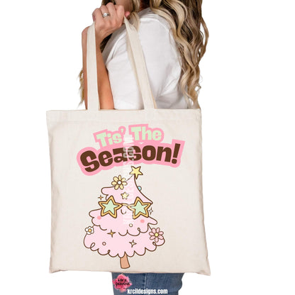 Christmas Tote Bags by KrcilDesigns.com | Graphic design on a canvas tote bag, features a cute pink Christmas tree wearing star-shaped sunglasses, decorated with pastel stars and pastel daisy flowers, with text that reads: "Tis' The Season!" in bold retro-style pink, green, and brown lettering curved above the tree.