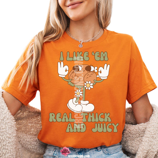 Funny Thanksgiving Shirts by KrcilDesigns.com | Graphic design on a orange t-shirt, featuring a playful cartoon turkey leg retro character with arms, legs, sunglasses, and daisy flowers, striking a sassy pose with both hands making the 'okay' sign. Surrounded by retro-style sage green text in all caps that reads: "I LIKE ‘EM REAL THICK AND JUICY"