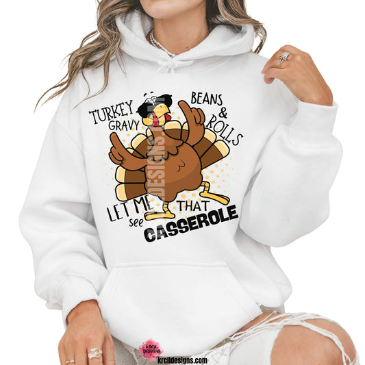Funny Thanksgiving Shirts by KrcilDesigns.com | Graphic design on a white hoodie, featuring a cartoon turkey wearing sunglasses, the turkey is brown with a red wattle, yellow beak and feet, with yellow dots as a background. The words are scattered around the turkey in bold black text that reads: "Turkey Gravy Beans & Rolls LET ME SEE THAT CASSEROLE"