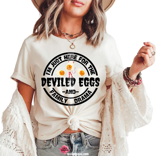 Sassy Graphic Tees T-Shirts by KrcilDesigns.com | Graphic design on a white t-shirt, featuring a bold circular design and bold black text that reads: "I'm Just Here For The Deviled Eggs and Family Drama" with graphics of a devil deviled egg dressed up with a devil's tail, horns, and pitchfork, on each side are two deviled eggs.