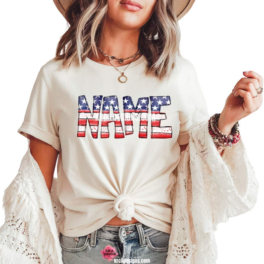USA Flag 4th of July Personalized Name Shirts by KrcilDesigns.com | Graphic design on a white t-shirt, features your name, in bold, distressed block letters filled with a vintage American flag pattern—blue with white stars on top and red and white stripes on the bottom.
