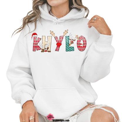 Christmas Personalized Name Shirts, Sweatshirts, Hoodies, by KrcilDesigns.com | Graphic Design on a white hoodie, features your name, in name style option: "Christmas" where the designs of the letters are different festive Christmas patterns. The letters don a Santa Hat, Rudolph's Red Nose, and Reindeer Antlers. Santa and his Reindeer are playing Peek-a-Boo and are peeking out of letters.