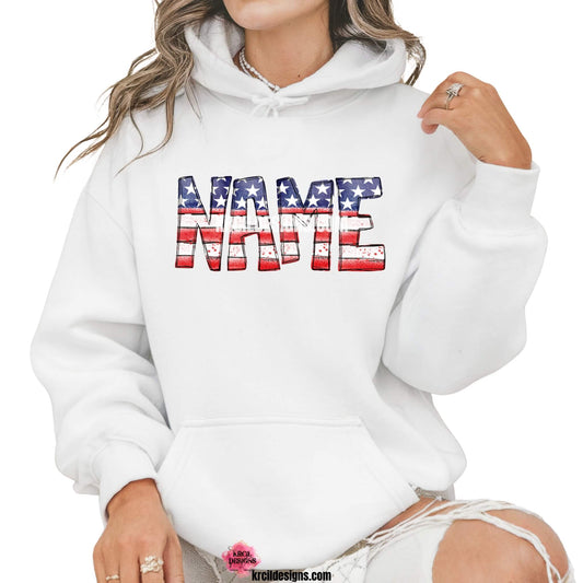 USA Flag 4th of July Personalized Name Shirts, Sweatshirts, Hoodies by KrcilDesigns.com | Graphic design on a white hoodie, features your name, in bold, distressed block letters filled with a vintage American flag pattern—blue with white stars on top and red and white stripes on the bottom.