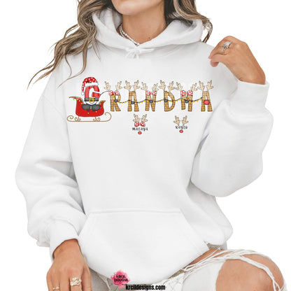 Christmas Personalized Name Shirts, Sweatshirts, Hoodies, by KrcilDesigns.com | Graphic Design on a white hoodie, reads: "GRANDMA" stars a "G" that's gone full Santa mode, dressed up in Santa's Suit and Santa's Hat, riding in Santa's sleigh with twinkling Christmas lights, while the rest of the "Grandma" letters are transformed into Santa's Reindeer. Featuring reindeer antlers, bows, and Rudolph's Red Nose. Add grandkids names as little reindeer! Not just for Grandma, we have them for everyone!