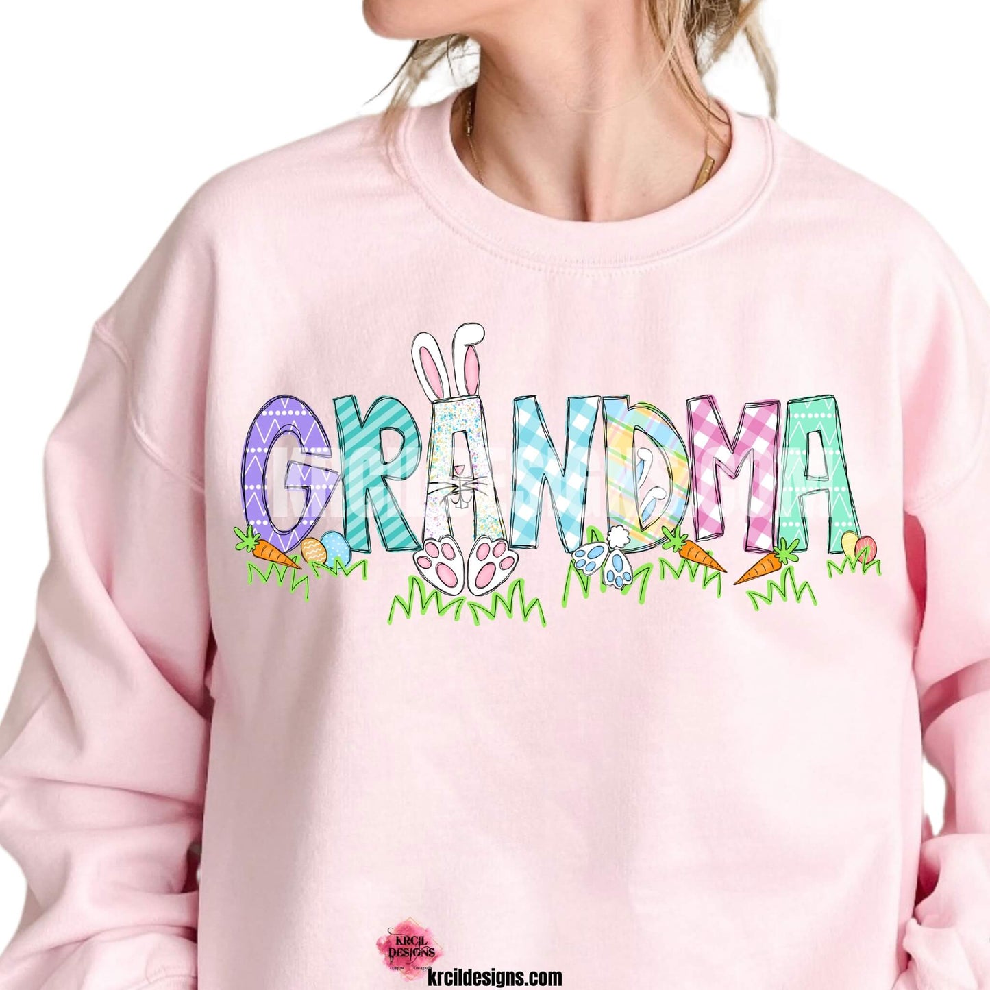 Easter Personalized Name Shirts, Sweatshirts and Hoodies by KrcilDesigns.com | Light pink crewneck sweatshirt, features your name, the letters are in different easter pastel patterns, one letter has a pink or blue Easter bunny character with bunny ears, bunny feet, and bunny tail, other letters have bunnies hopping into them. Surrounding the letters are colorful Easter eggs, carrots, and the letters atop a row of grass. Add the kids names and make it truly yours!