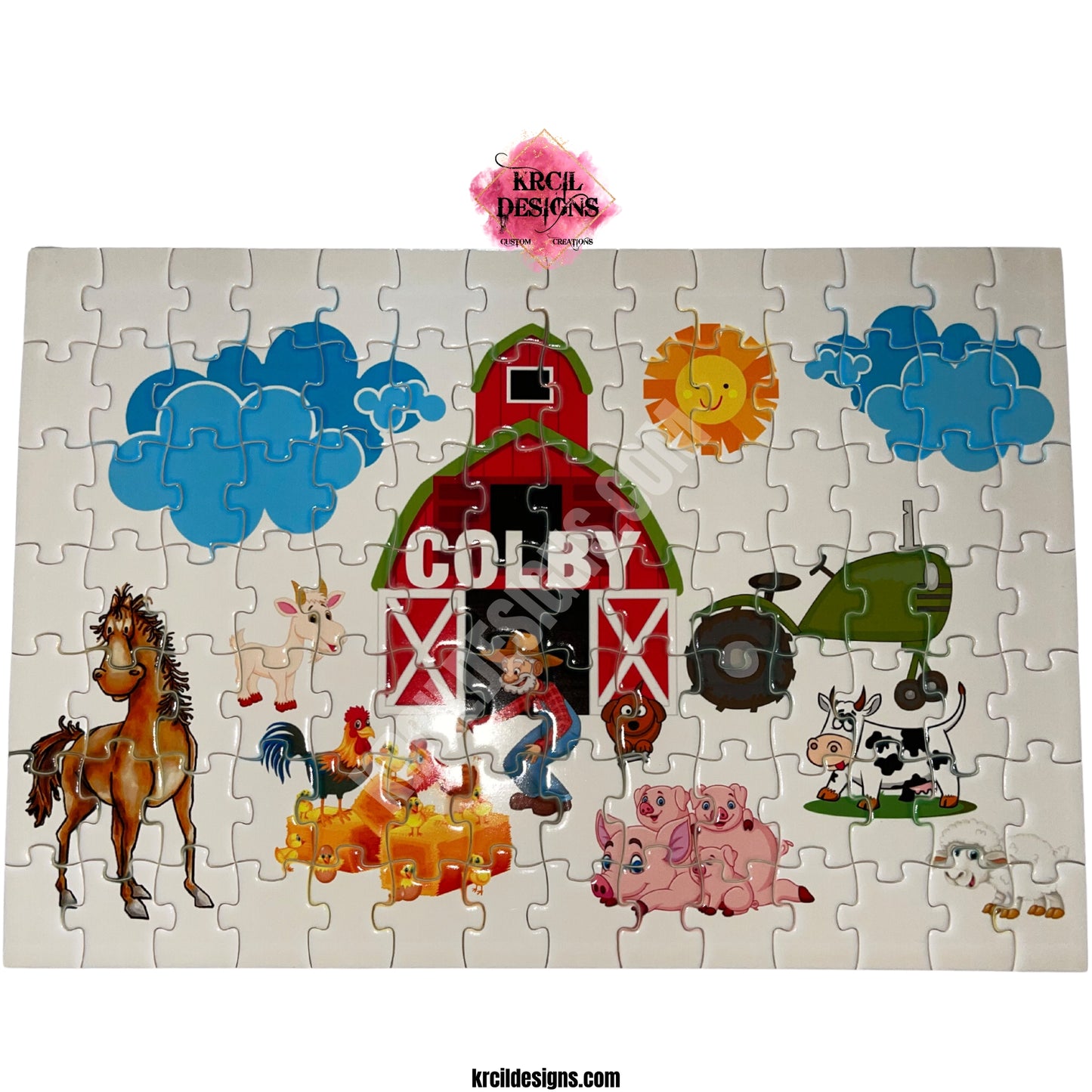 Old MacDonald Farm Personalized Puzzle by Krcil Designs | This charming puzzle features a white backdrop and showcases a barn, sun, fluffy clouds, a delightful cast of farm animals, and a green tractor. Arrives fully assembled with a reference picture. Learning about farm life has never been this fun, making it the perfect gift for little farmers. It's easy, educational, and fun – a delightful way to spark their love for the farm! Give the ultimate gift by adding a tote bag! KrcilDesigns.com