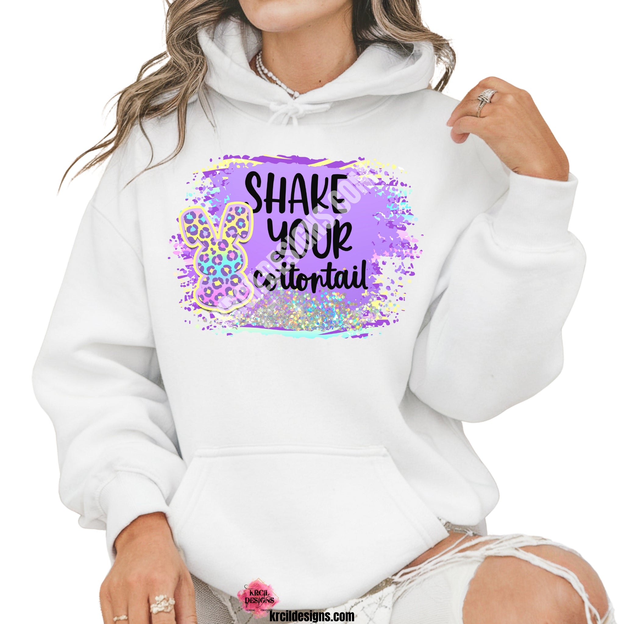 Shake Your Cottontail Easter Sweatshirt by Krcil Designs | Make a fashion statement with our sweatshirts and hoodies! Our buttery soft cozy shirts will become your new weekend bestie! Get ready to hop into fun with our "SHAKE YOUR cottontail" Easter sweater! Our graphic design, showcases a pastel cheetah print bunny and vibrant splashes of Easter colors. This Easter, celebrate in style with matching family shirts—perfect for family photos! Shop Easter Sweatshirts and Hoodies at KrcilDesigns.com