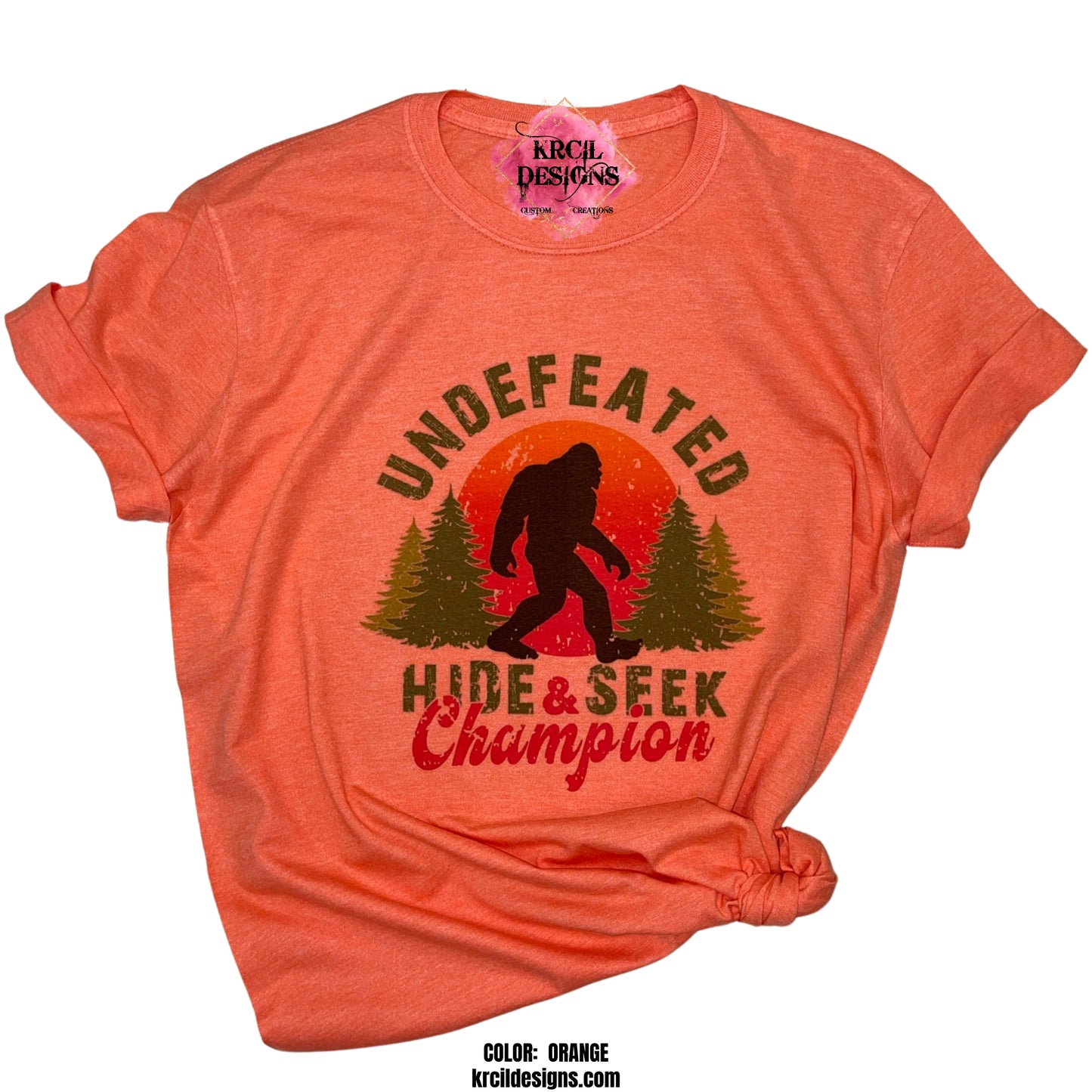 ORANGE | Show off your sense of humor with our Bigfoot T-Shirt "Undefeated Hide & Seek Champion" Sasquatch T-Shirt by Krcil Designs! Featuring Bigfoot! The Bigfoot Tee that's a conversation starter at the Bigfoot Festival or on Bigfoot Day. Don't miss the fun — grab your Sasquatch Tee before it disappears into the woods! Give the gifts for Bigfoot lovers that make them roar with laughter! Keep the Bigfoot Legend Alive! Sasquatch: The Legend of Bigfoot! Shop Bigfoot Gifts at KrcilDesigns.com