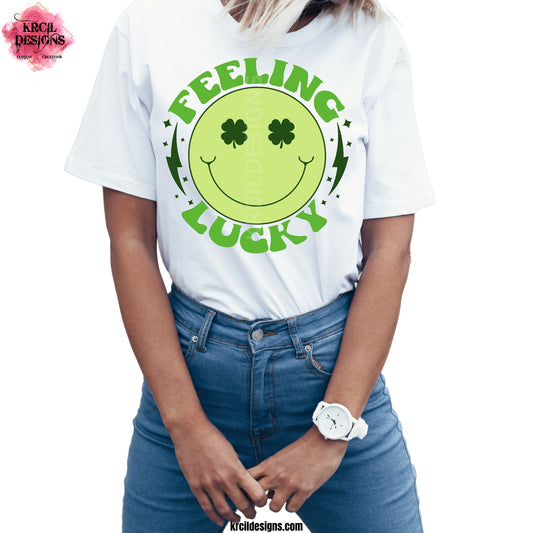 Smiley Face Feeling Lucky St. Patrick's Day T-Shirt by Krcil Designs! | Make a fashion statement with our graphic tees t-shirts! Our buttery soft cozy tees will become your new weekend bestie! Get your green on with our smiley face "FEELING LUCKY" St. Patrick's Day tee. Meet our St. Patty's Day shirt, "FEELING LUCKY" retro graphic tee, featuring retro letters, in shades of green, a smiley face rocking shamrock eyes, and lighting bolts on each side. Shop St. Patrick's Day Shirts at KrcilDesigns.com