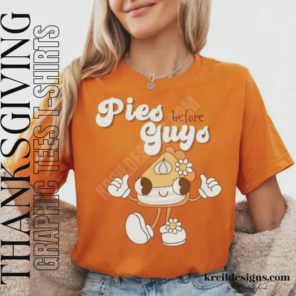 Funny Thanksgiving Shirts by KrcilDesigns.com | Graphic design on a orange t-shirt, featuring a playful cartoon piece of pumpkin pie retro character with arms, legs, and daisy flowers, striking a sassy pose with both hands making the 'thumbs up' sign. Surrounded by retro-style white text that reads: "Pies before Guys"