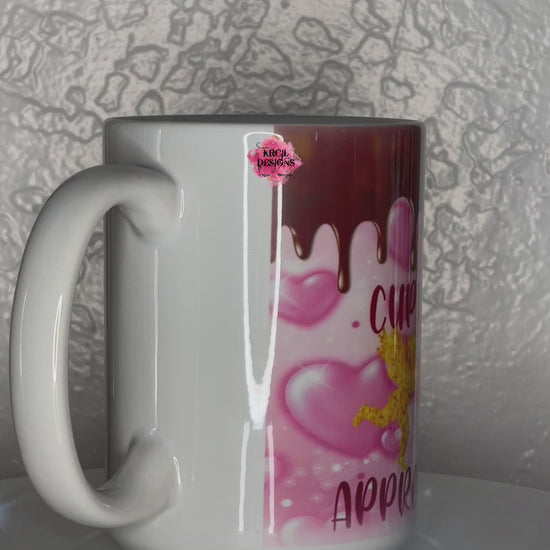 Valentines Coffee Mugs by Krcil Designs | A white ceramic mug and a graphic design that wraps around the mug. Hot cocoa drips from top onto a bubbly pink hearts background, faux glitter cupid and his arrow. Dark pink text that reads: Cupid Approved Hot Cocoa. | Shop Valentines Mugs at KrcilDesigns.com