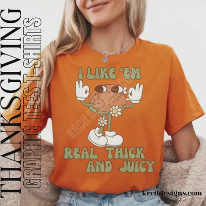 Funny Thanksgiving Shirts by KrcilDesigns.com | Graphic design on a orange t-shirt, featuring a playful cartoon turkey leg retro character with arms, legs, sunglasses, and daisy flowers, striking a sassy pose with both hands making the 'okay' sign. Surrounded by retro-style sage green text in all caps that reads: "I LIKE ‘EM REAL THICK AND JUICY"