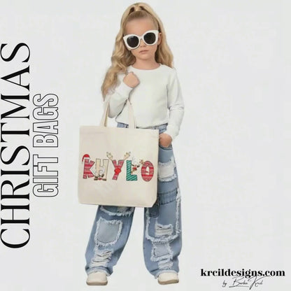 Christmas Personalized Tote Bags by KrcilDesigns.com | Graphic Design on a canvas tote bag, features your name, in name style option: "Christmas" where the designs of the letters are different festive Christmas patterns. The letters don a Santa Hat, Rudolph's Red Nose, and Reindeer Antlers. Santa and his Reindeer are playing Peek-a-Boo and are peeking out of letters.